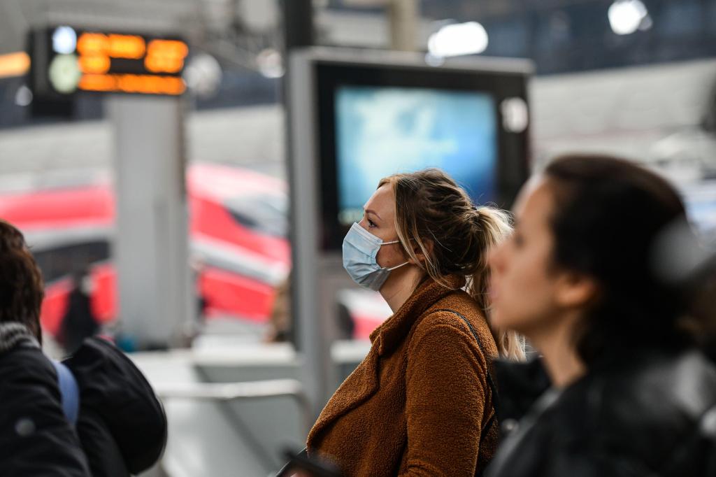 A woman wearing a face mask on a train platform