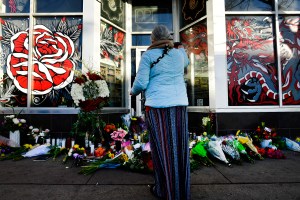 A woman who described herself as a healer waves ceremonial smoke over a makeshift memorial outside Sol Tribe Custom Tattoo and Body Piercing shop in Denver, Colorado. (Helen H. Richardson/MediaNews Group/The Denver Post