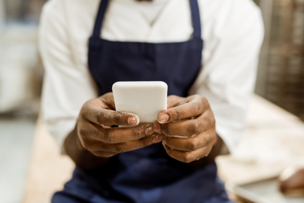 Negative restaurant reviews – chef holding a phone and checking reviews.