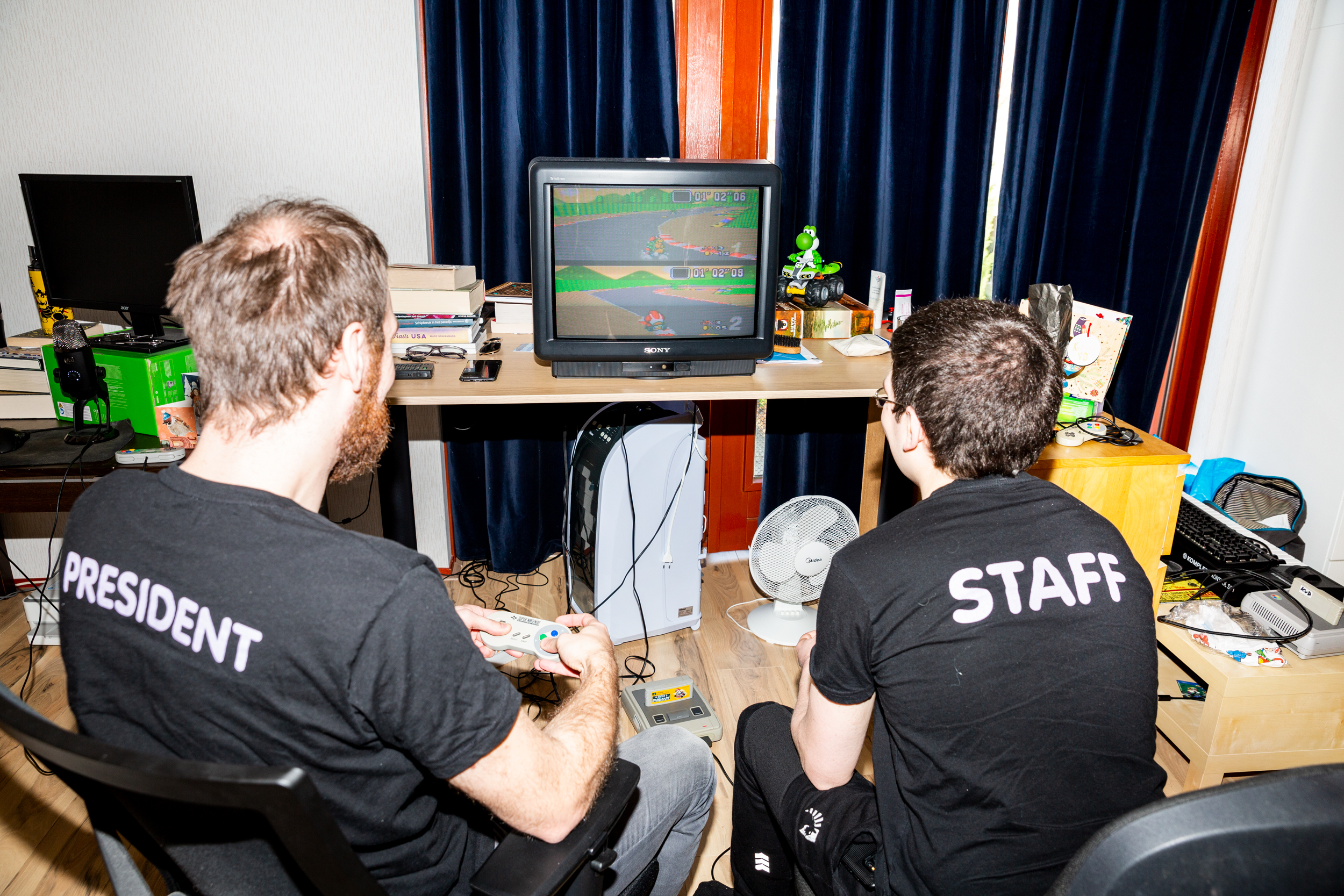 Speedrunning, Marieka de Bra, gaming – Photograph of two men in black t-shirts playing Mario Kart on a small television