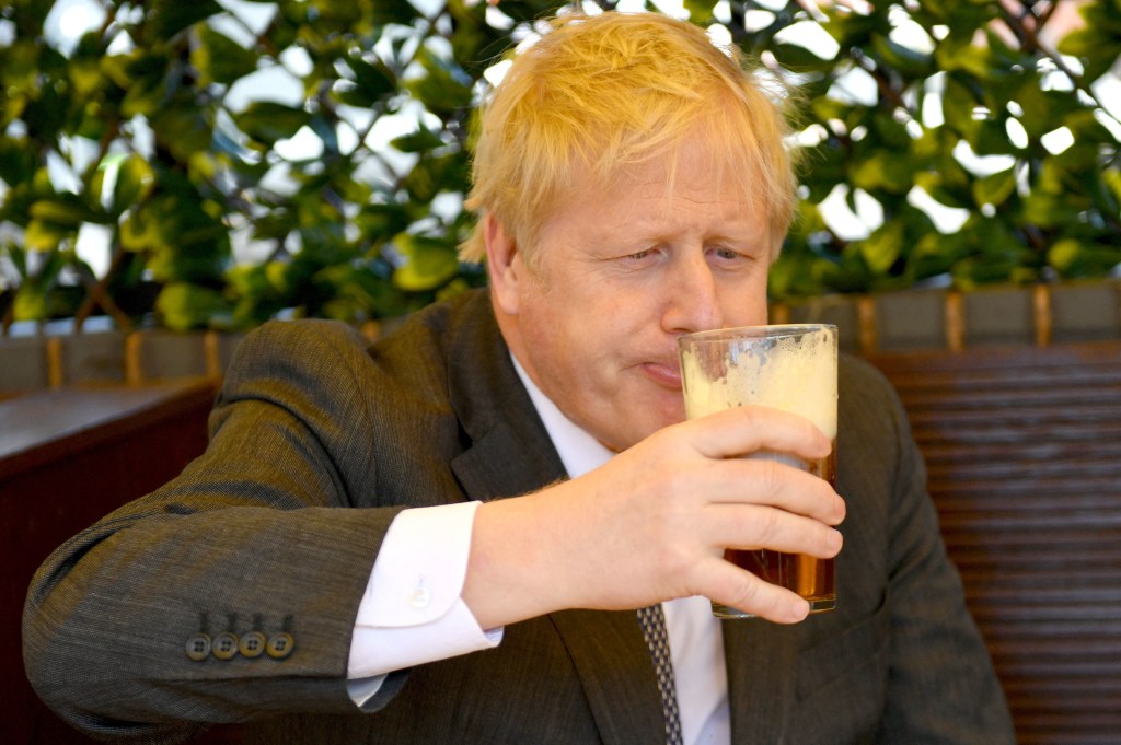 Boris Johnson sipping beer at a pub in 2021. Photo: Jacob King / POOL / AFP