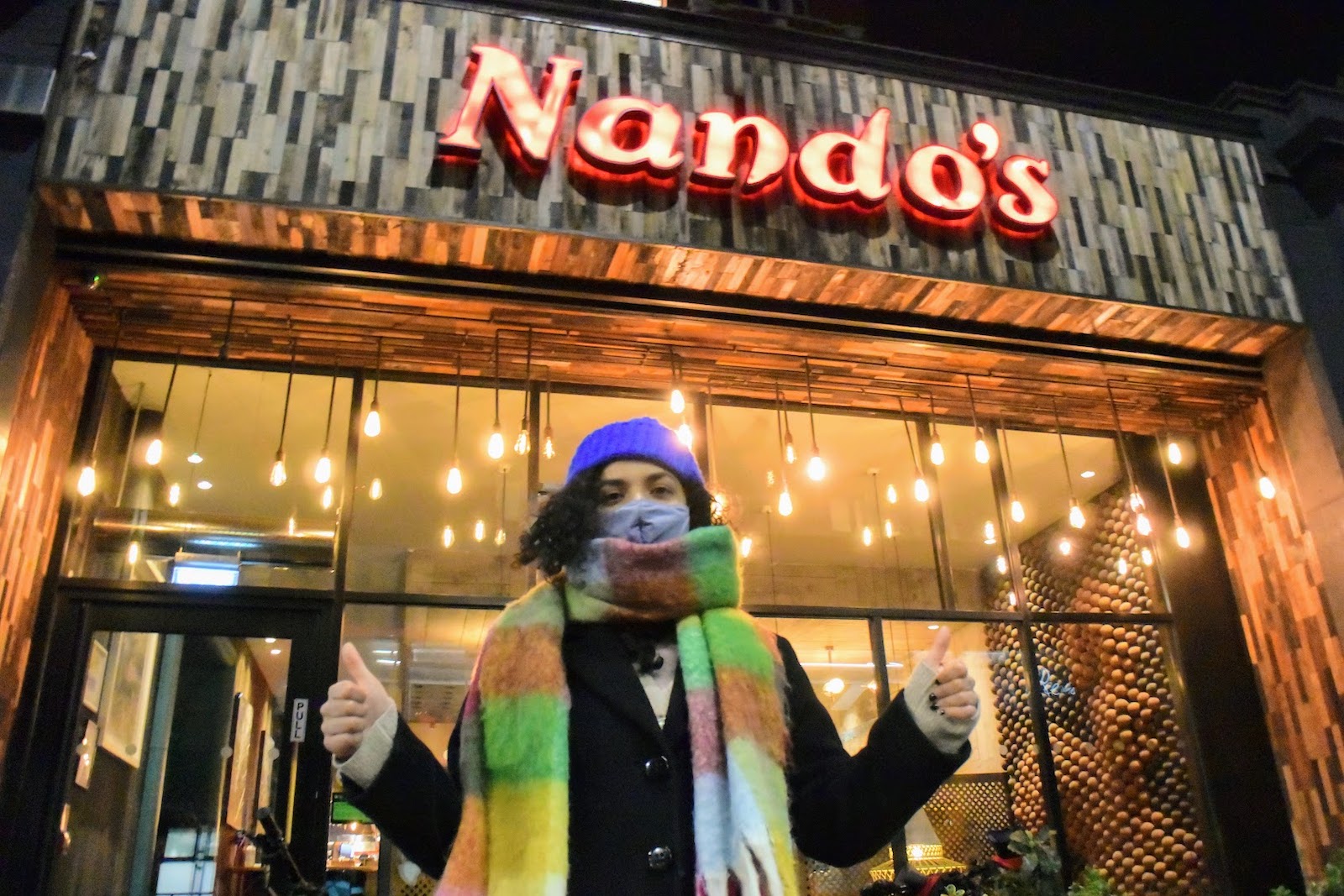 Carla Abreu stands in front of a Nando's making a thumbs up sign