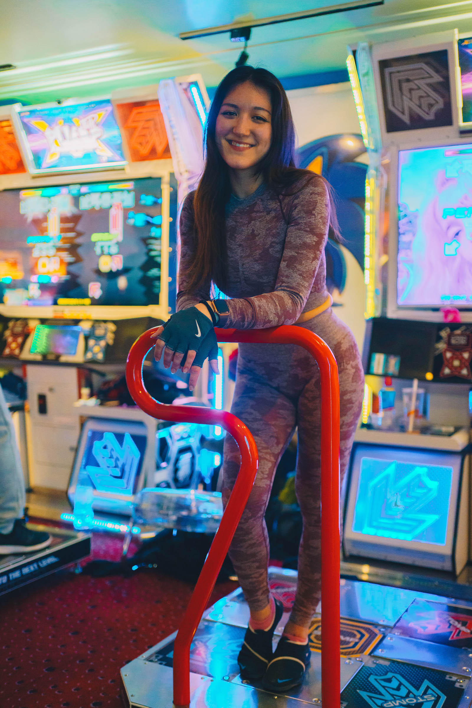 Alisa Teterina standing on a Dance Dance Revolution arcade game unit