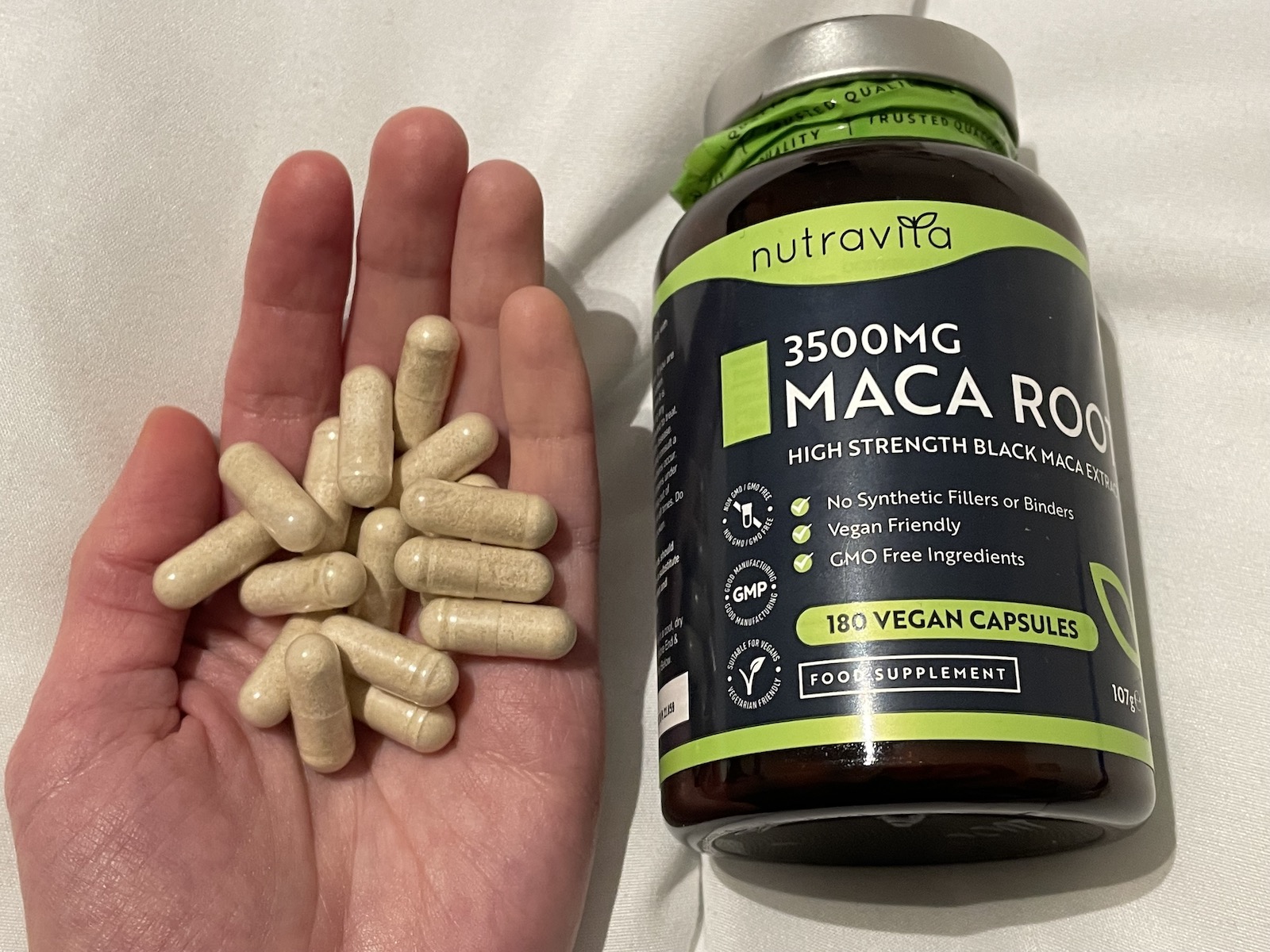 A hand with a handful of powdered maca root capsules, a supposed aphrodisiac