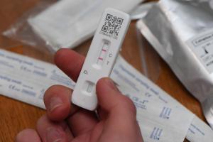 A positive Covid-19 lateral flow test held in the hand showing the two red marking lines