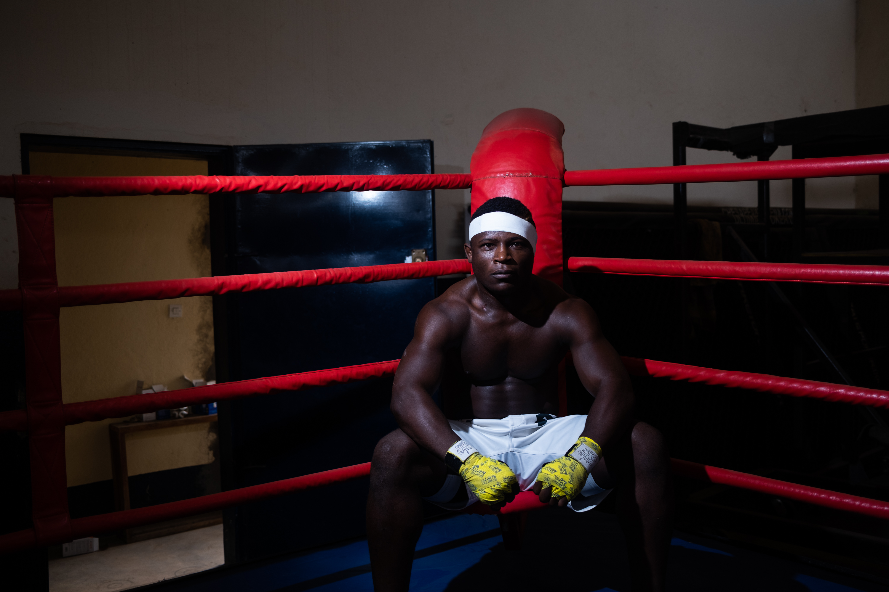 Foundation Ngannou, Batié, Cameroon – Man in white shorts and a white sweatband, sitting in a corner of a ring.