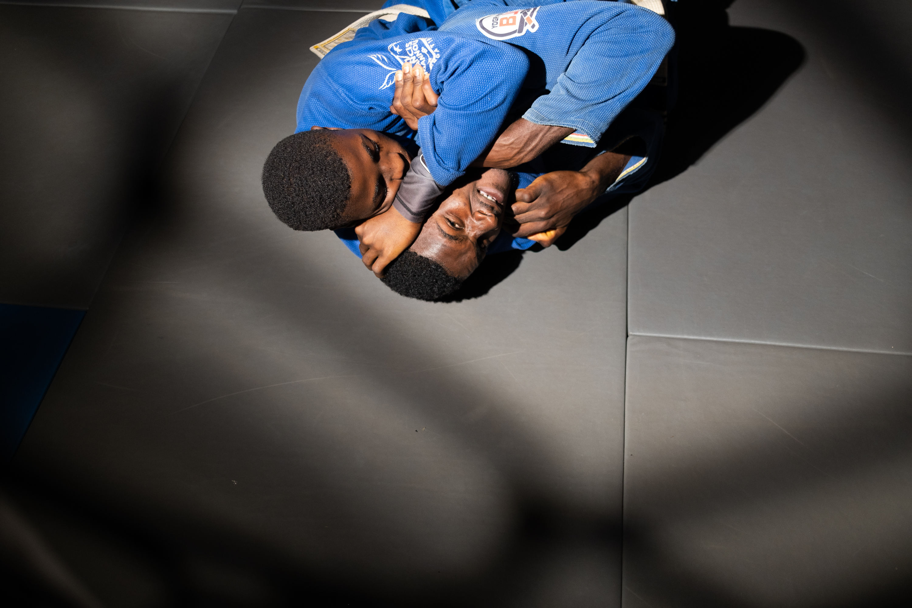 Foundation Ngannou, Batié, Cameroon – One teenager holding another in a chokehold on a dark grey mat.