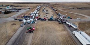 Anti-mandate demonstrators gather as a truck convoy blocks the highway the busy U.S. border crossing in Coutts, Alberta