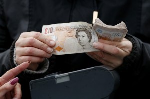 A woman points to a man holding a ten pound note