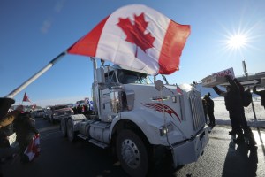 Supporters wave flags and cheer as a convoy of trucks passes in Rigaud, Quebec, Canada, on Friday, Jan. 28, 2022.​ "Freedom truckers" have made their way around the country, including at at least two major border crossings. Christinne Muschi/Bloomberg via