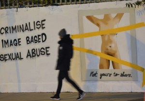 Someone walks by art critiquing revenge porn in Dublin, Ireland by artist Emmalene Blake in November 2020.