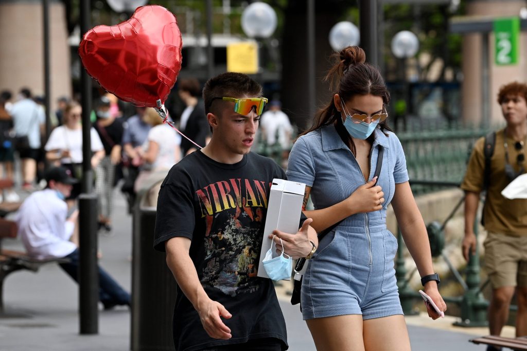 Ein Mann und eine Frau gehen über einen Platz mit vielen Menschen. Der Mann trägt ein Nirvana-Shirt und einen Luftballon in Herzform. Wir haben die 10 meistgegoogelten Fragen zum Valentinstag beantwortet