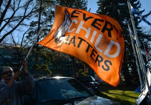 ​A man holds an "Every Child Matters" flag at an anti-vaccine mandate protest