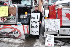 A man holds a sign as truck drivers and their supporters gather to block the streets as part of a convoy of truck protesters against COVID-19 mandates on February 09, 2022 in Ottawa, Ontario.(Spencer Platt/Getty Images)