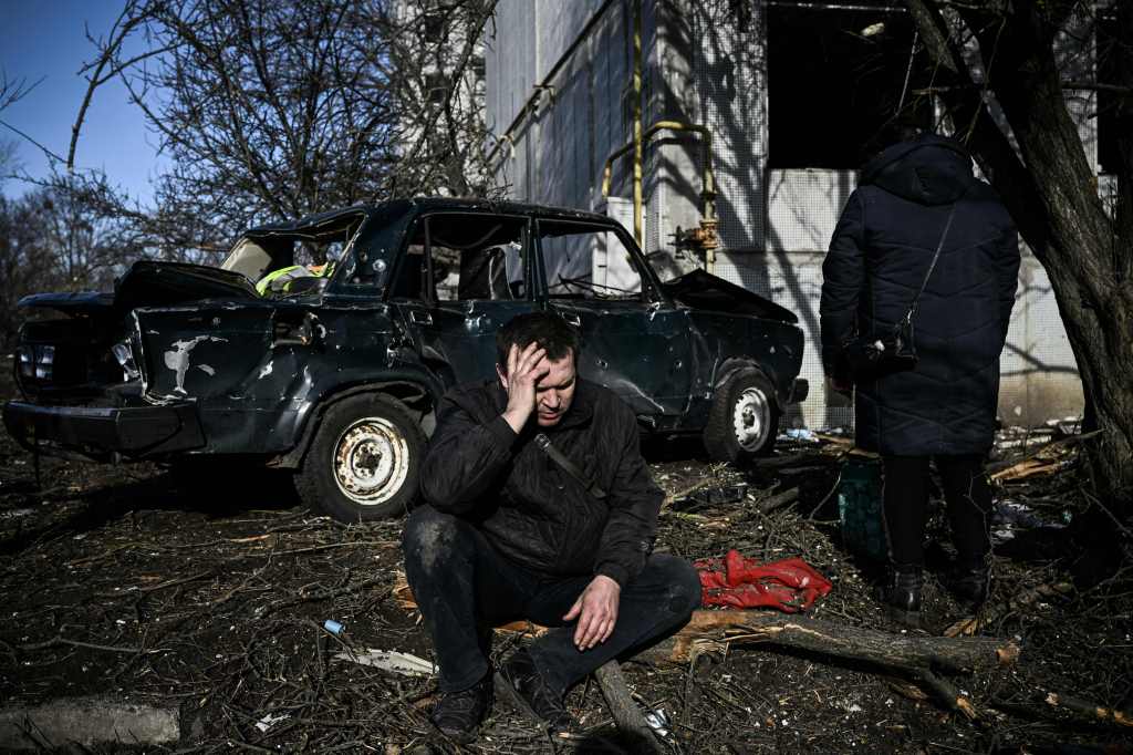 A man sits outside his destroyed building after bombings on the eastern Ukraine town of Chuguiv. Photo: ARIS MESSINIS/AFP via Getty Images