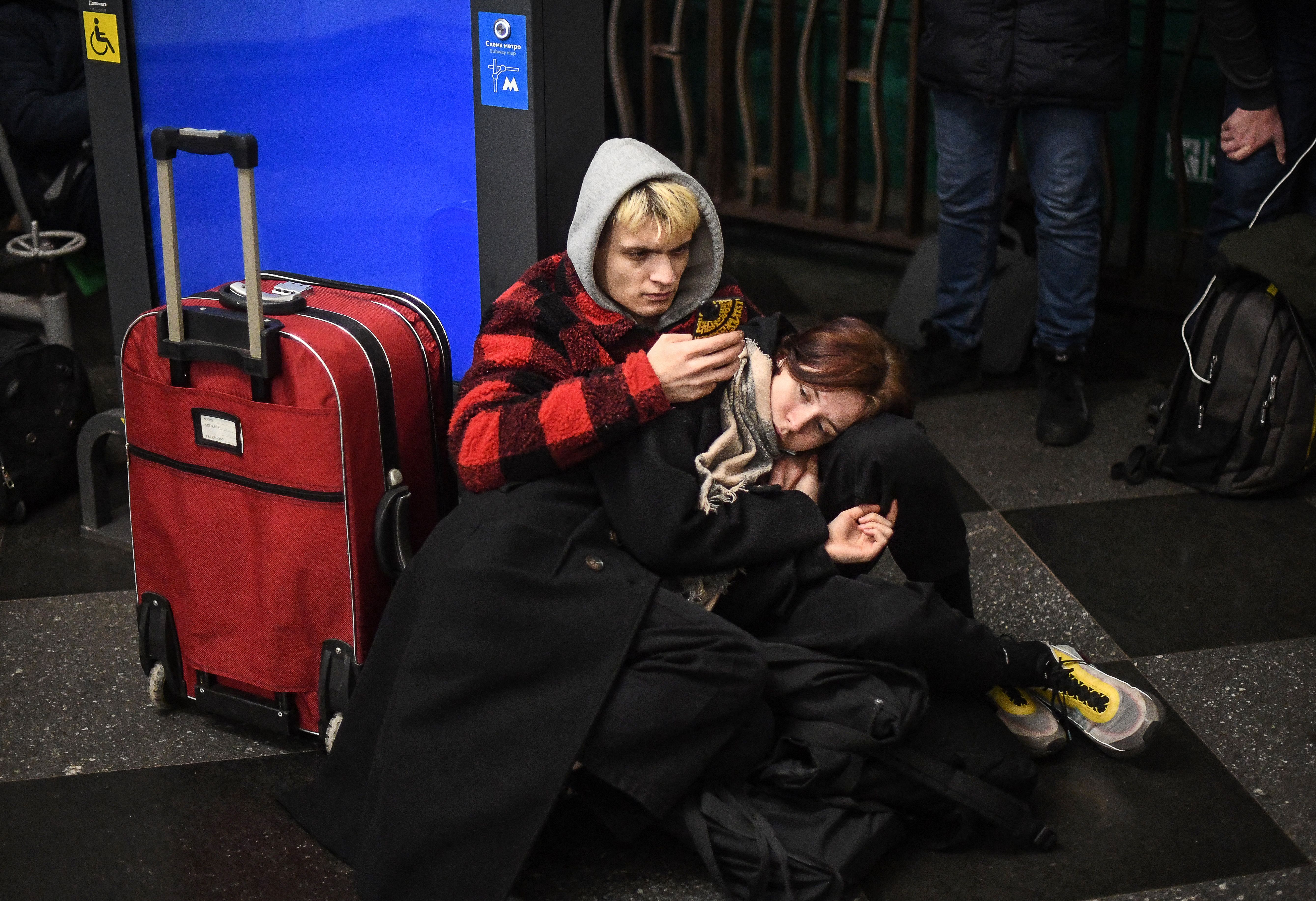 People use their phone as they take shelter in a metro station in Kyiv in the morning of February 24, 2022.