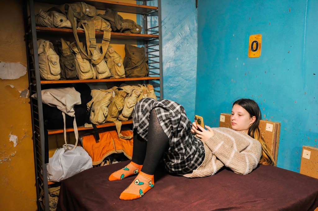 Young girl reading news in a bomb shelter in Kyiv. (Sergei Chuzavkov/SOPA Images/LightRocket via Getty Images)