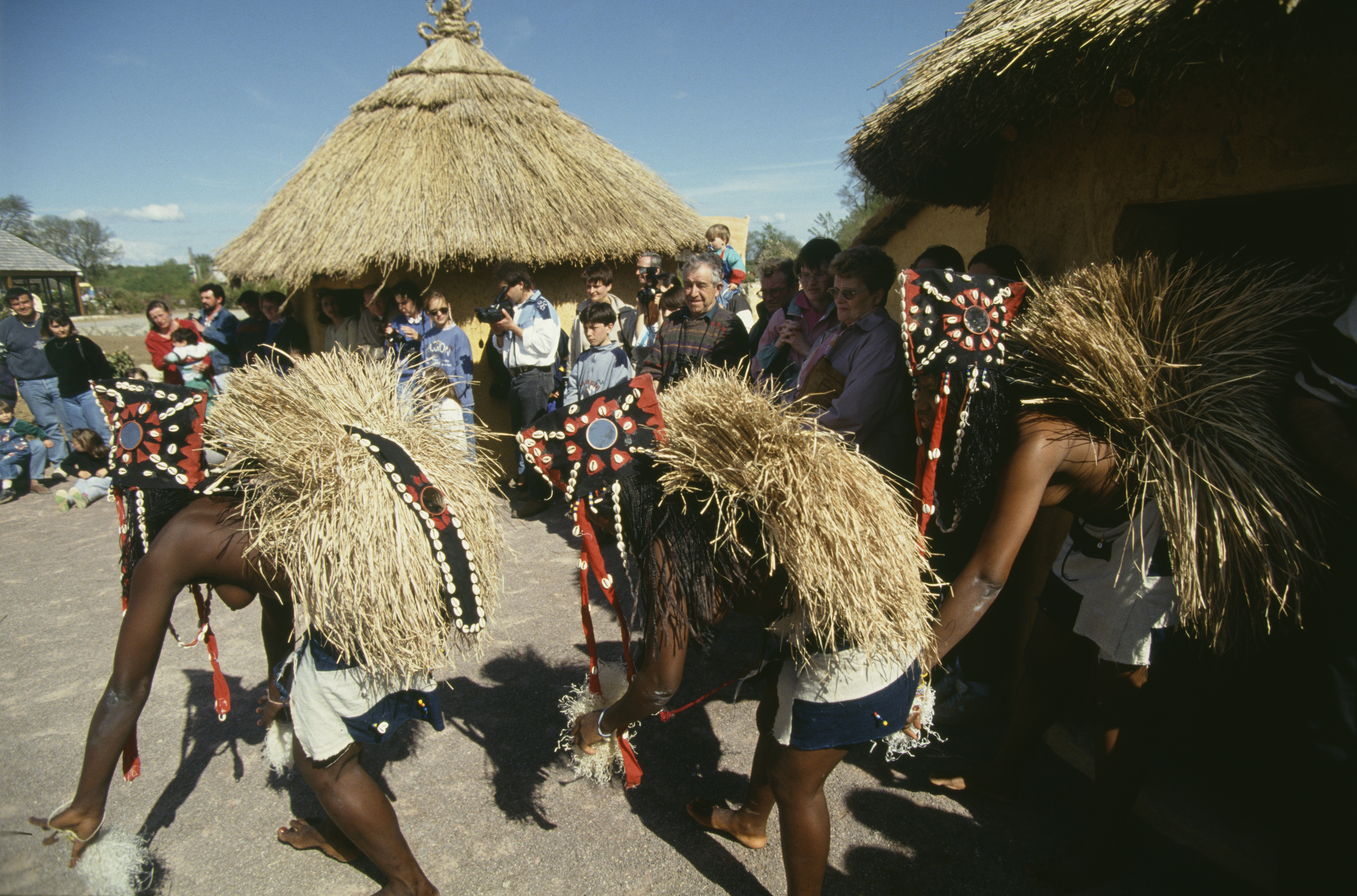 Bamboula's Village – three black women wearing traditional costumes made out of straw, cloth and beading, dancing bare-chested in front of a public of white people.