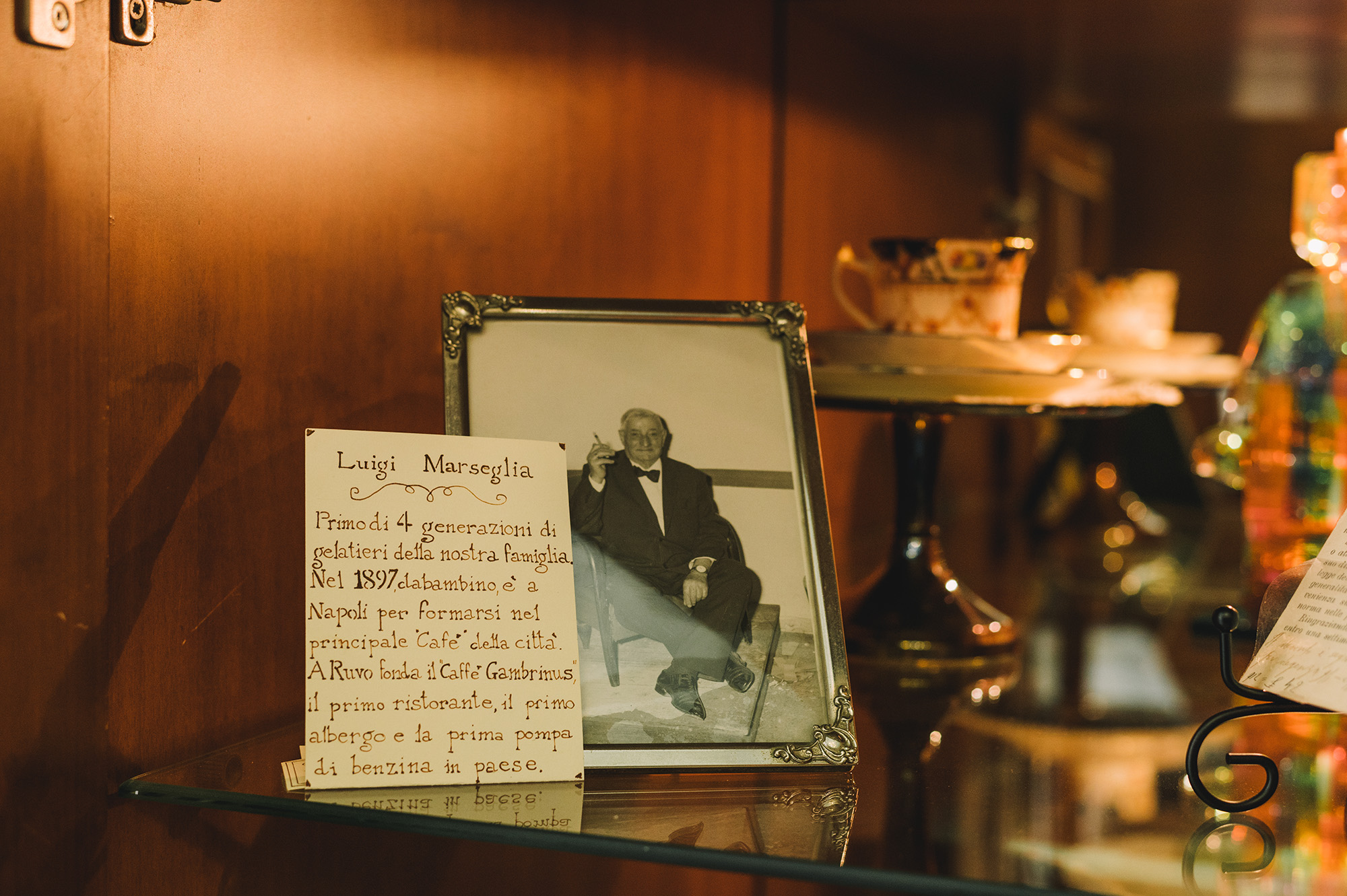 Mokambo, ice cream, Italy - Photograph of a framed photograph of an elderly man in a tuxedo smoking a cigarette.