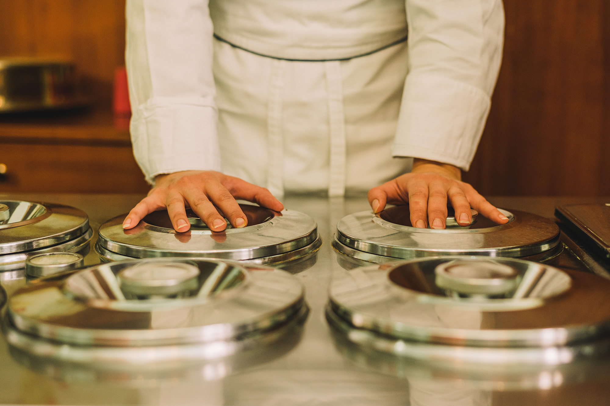 Mokambo, ice cream, Italy - Photograph of a human figure in chef's whites standing over four round, silver serving hatches.