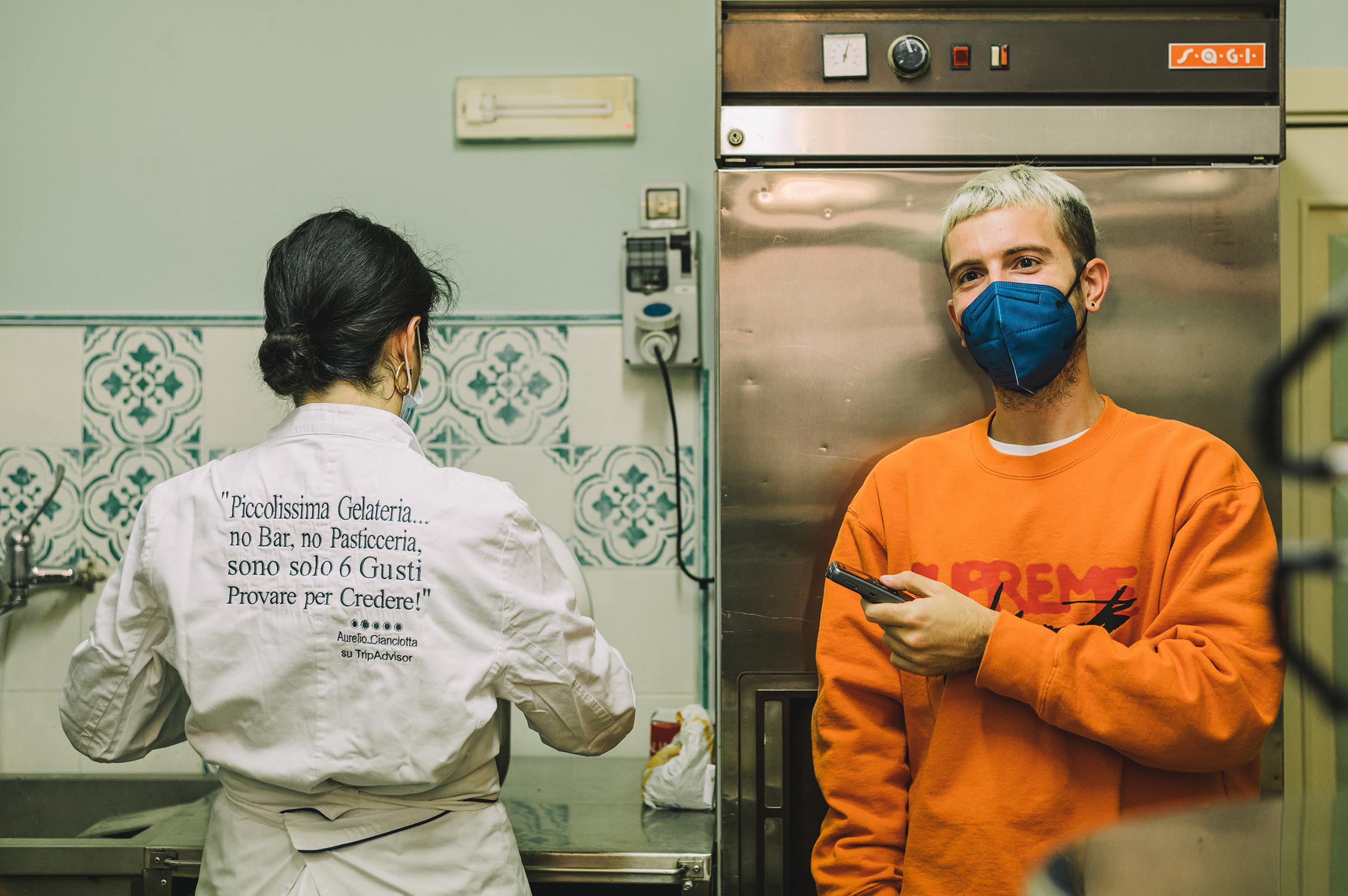 Mokambo, ice cream, Italy - Photograph of a blonde haired man in a blue face mask and an orange sweater stood in the restaurant kitchen next to a woman wearing chef's whites.