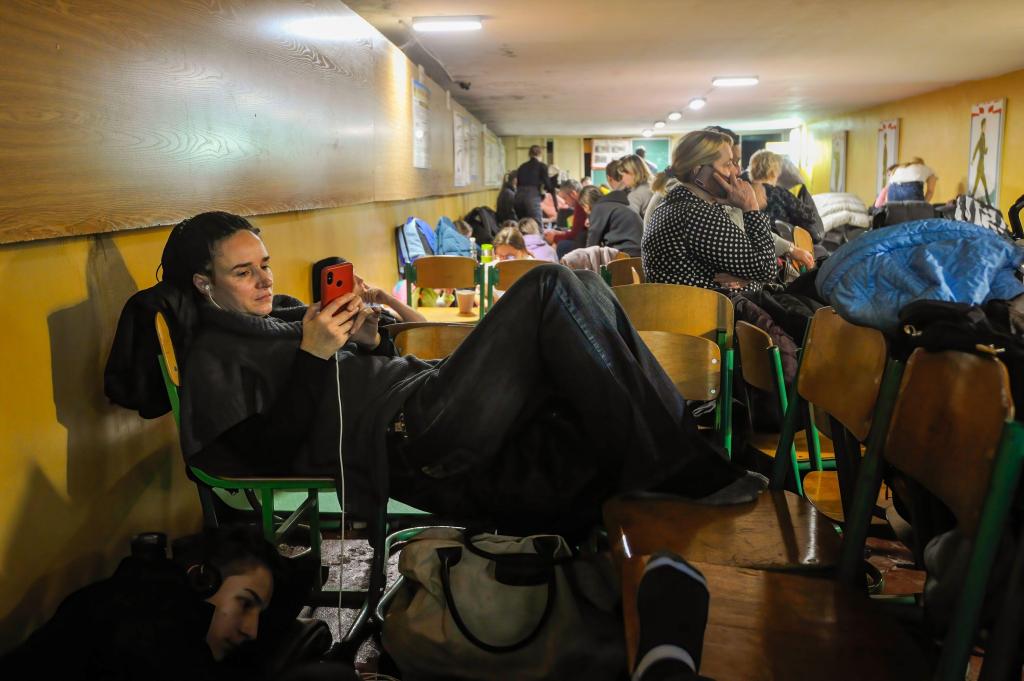 Women seen reading news at a bomb shelter in Kyiv