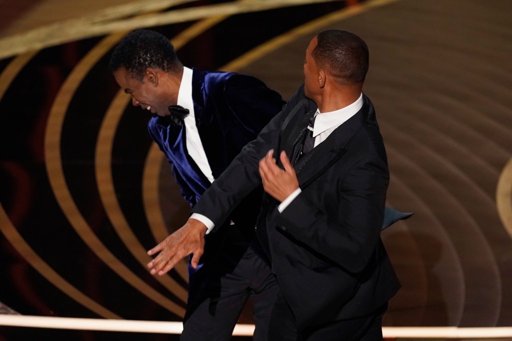 Will Smith, right, hits presenter Chris Rock on stage at the Oscars on Sunday, which launched a host of conspiracy theories.