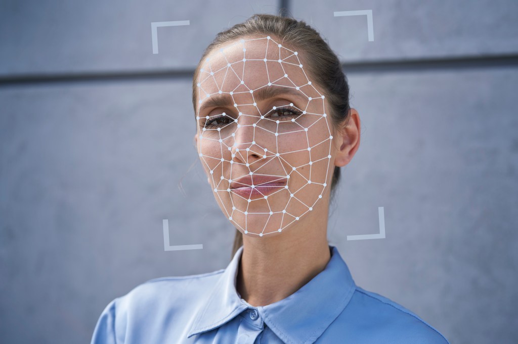 A woman in a blue shirt with a computer-generated mesh grid over her face.