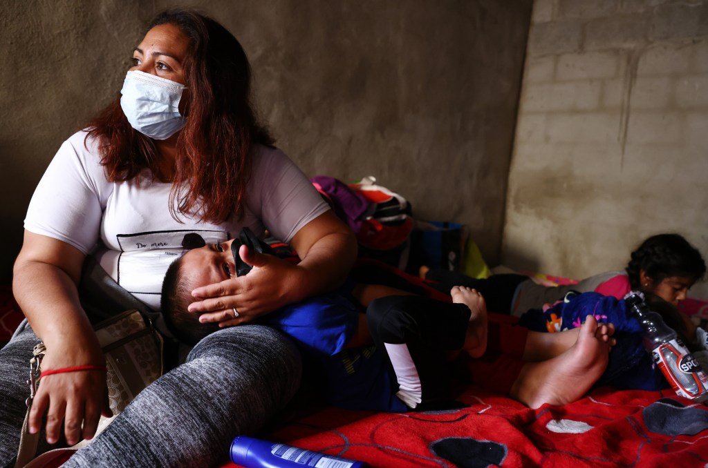 A mother holds her child as asylum-seeking migrants rest in a migrant shelter on July 21, 2021 in Tijuana, Mexico.