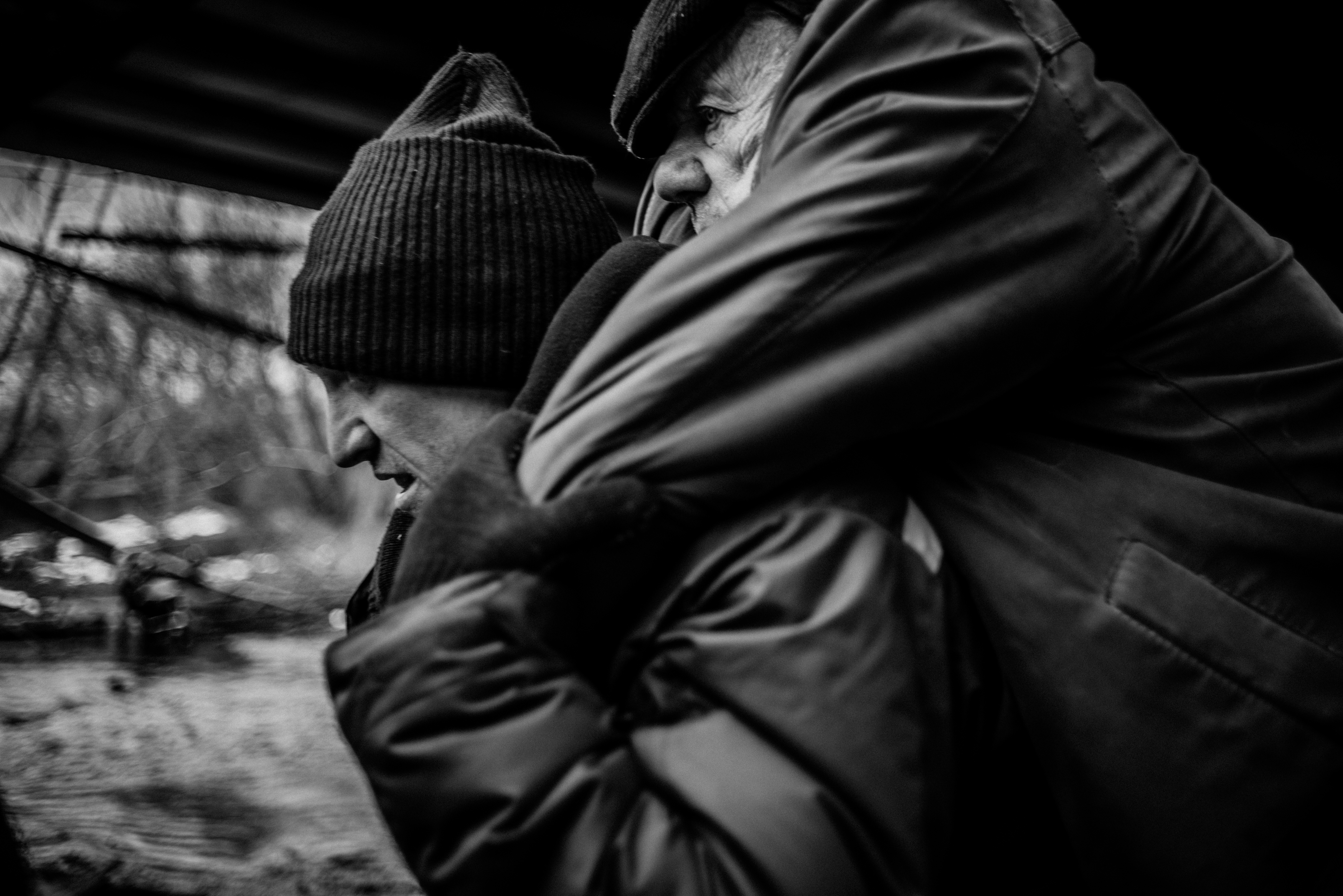 A volunteer carries a disabled older man across a destroyed bridge in Irpin.