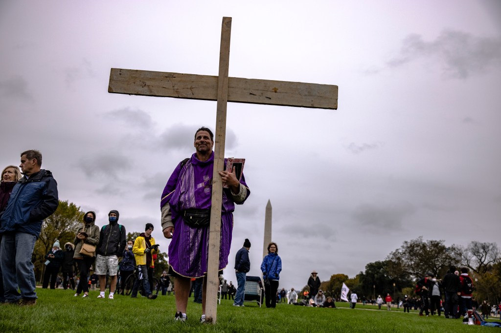 A man holds a cross