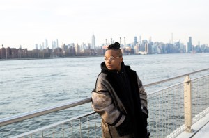 A transmasculine person standing by the water and looking into the distance