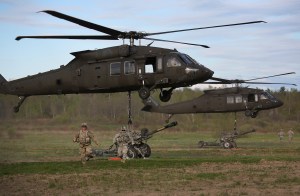 10th Mountain Division soldiers run after hooking their 105mm Howitzers to Blackhawk helicopters on a training mission on May 18, 2016 at Fort Drum, New York.