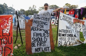 Tent Embassy resident Brad Clucas poses against a backdrop of signs inside the embassy in 2015 in Sydney, Australia.