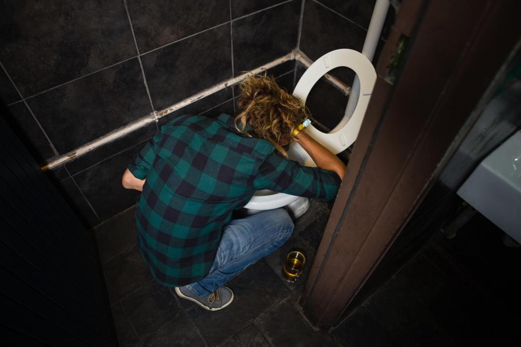 Man vomiting from smoking too much weed in toilet