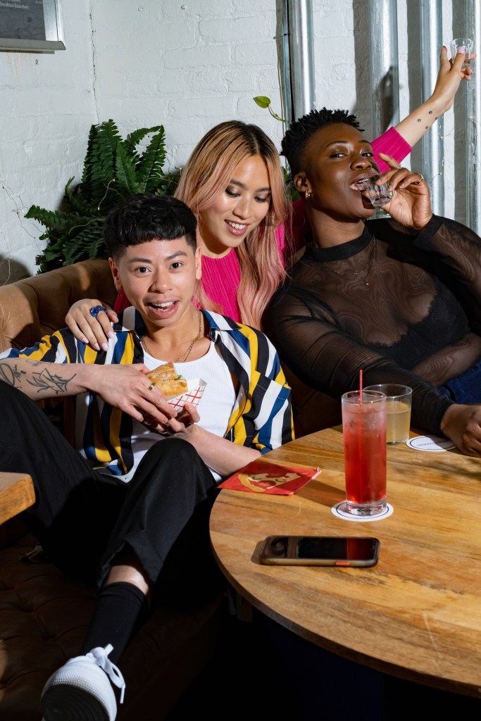 A group of friends of varying genders laughing over drinks (2)