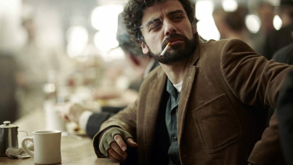 A screenshot of Oscar Isaac in Inside Llewyn Davis, smoking a cigarette and looking skeptical.