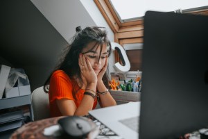 A young university student sat at desk looking stressed