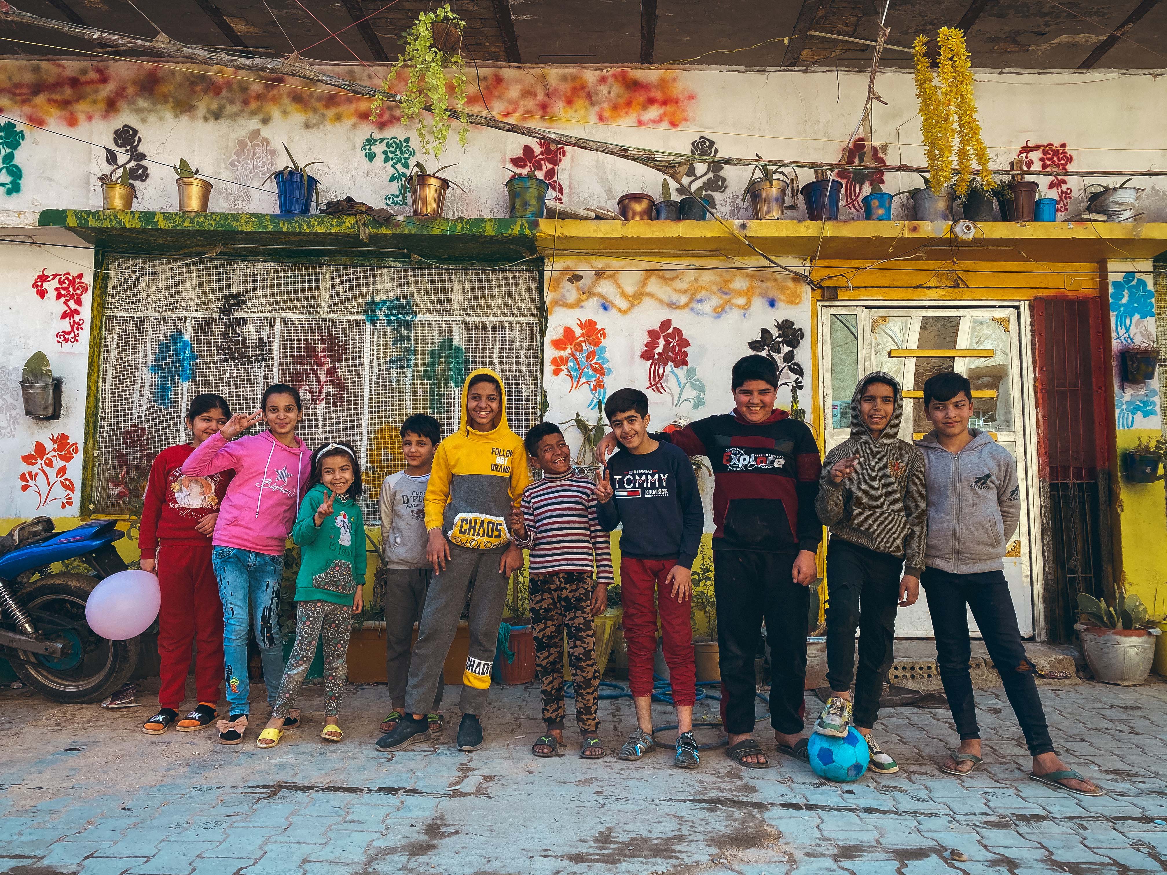 Baghdad, Al-Salam district – A group of young girls and boys standing in a row and smiling, posing with a blue football.