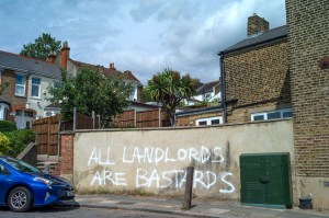 Graffiti reading 'All Landlords are Bastards' on a wall in Catford, London