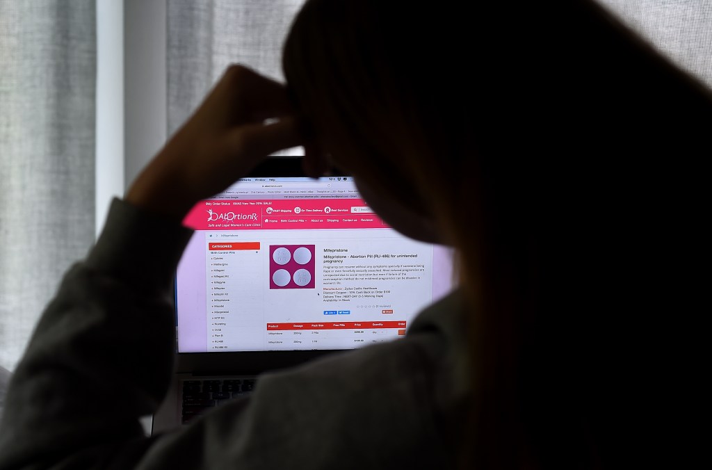 A person looks at a computer screen displaying a site that sells the abortion pill Mifepristone.