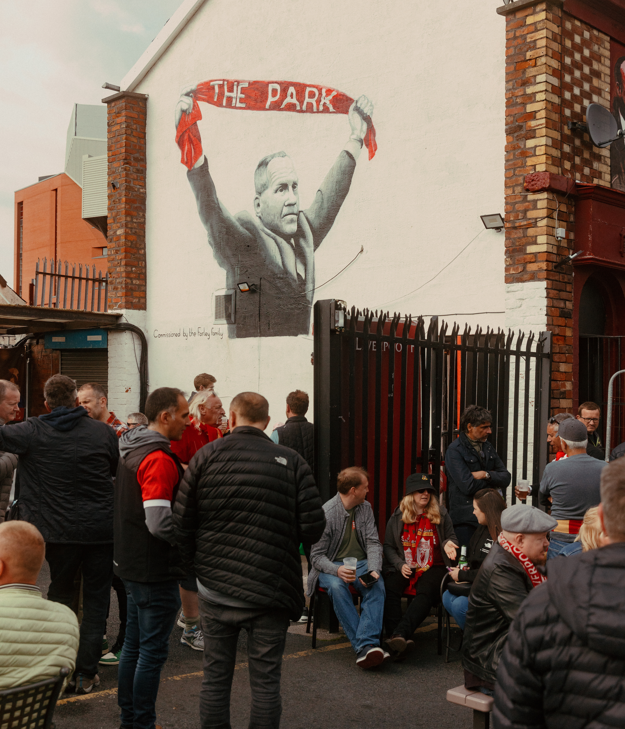 Fans gather in front of a mural of Bill Shankly in Liverpool