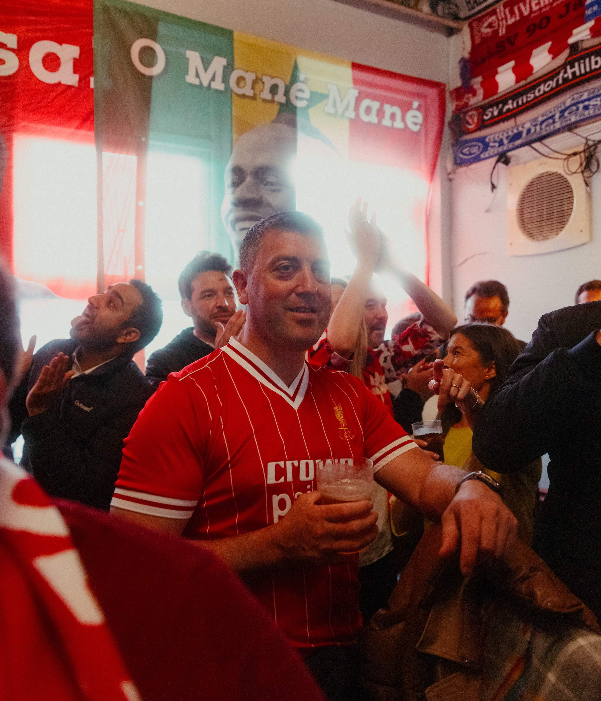 A Liverpool supporter holding a pint in a pub