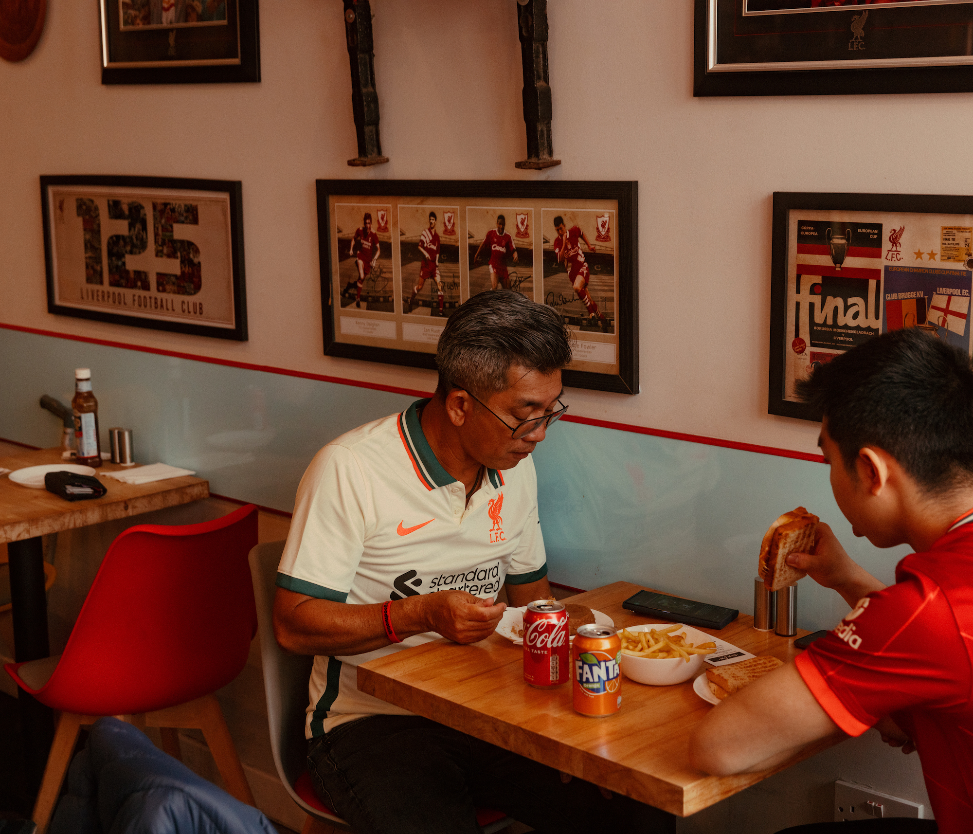 Two Asian Liverpool supporters eating food