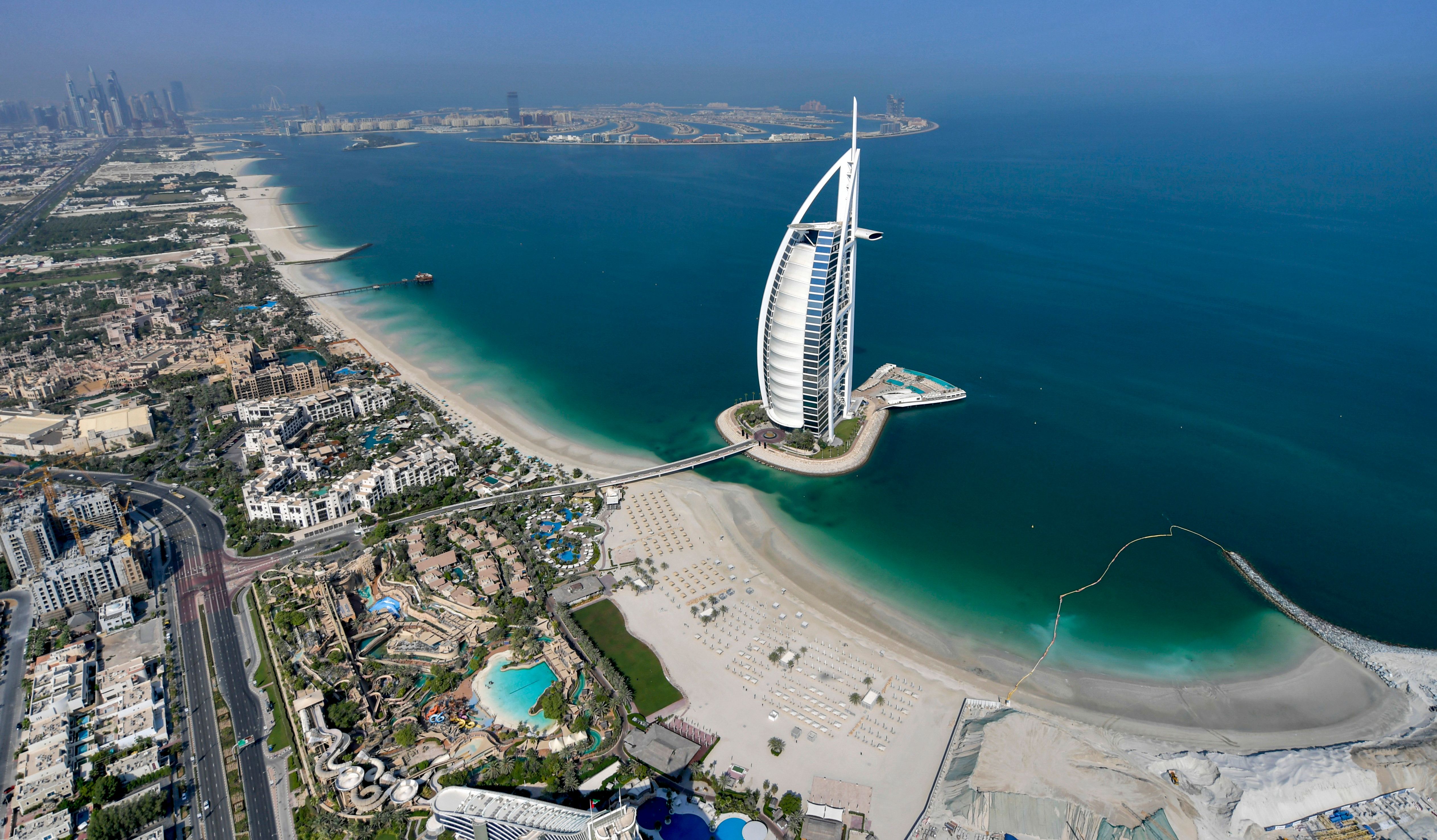 Luftaufnahme des Strands von Dubai mit einem markanten segelförmigen Hochhaus