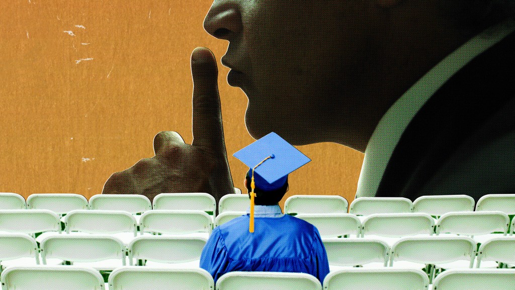 Graduating student sits in row of chairs while watching man in distance put silencing finger to his mouth.