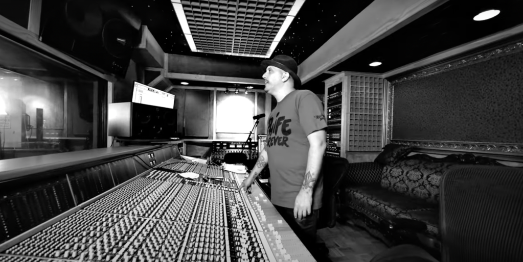 Starita stands in a recording studio, photographed in black and white.