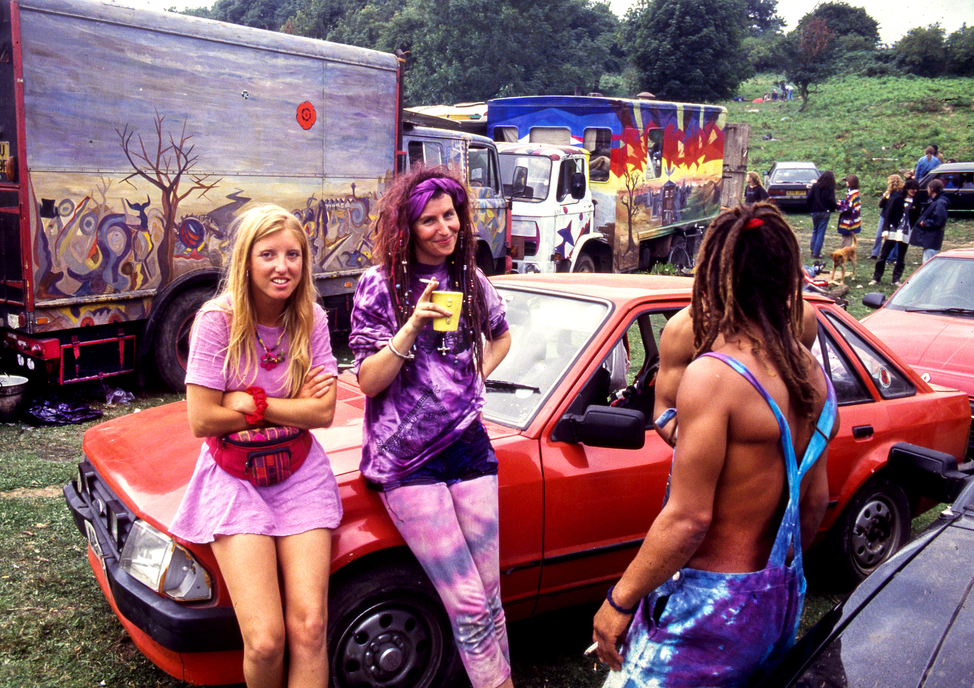 Three ravers at Castlemorton stood next to a red car, photo by Alan Lodge