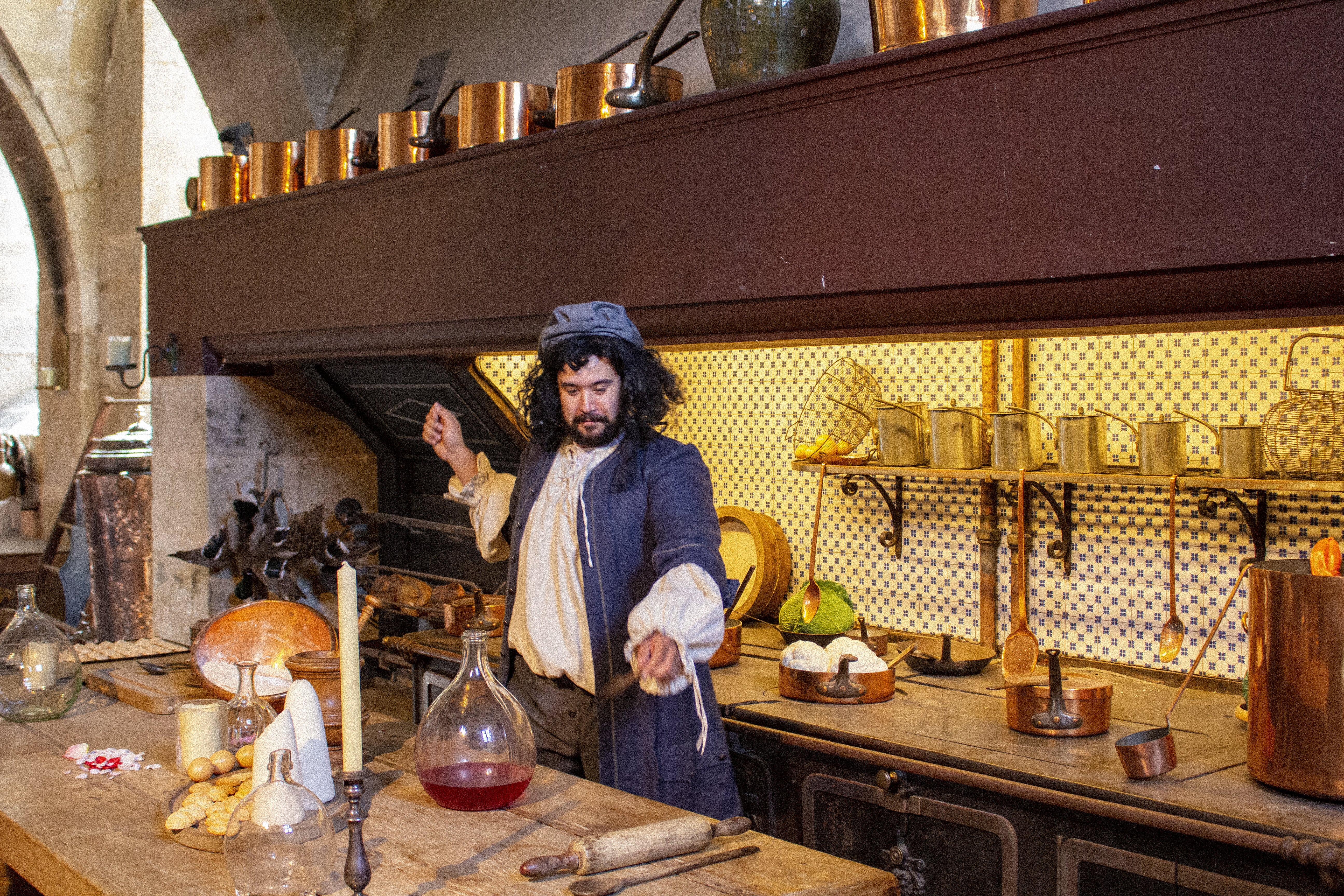 Château de Vaux-le-Vicomte – Man in a big historical kitchen, dressed in the fashion of the time, preparing food.