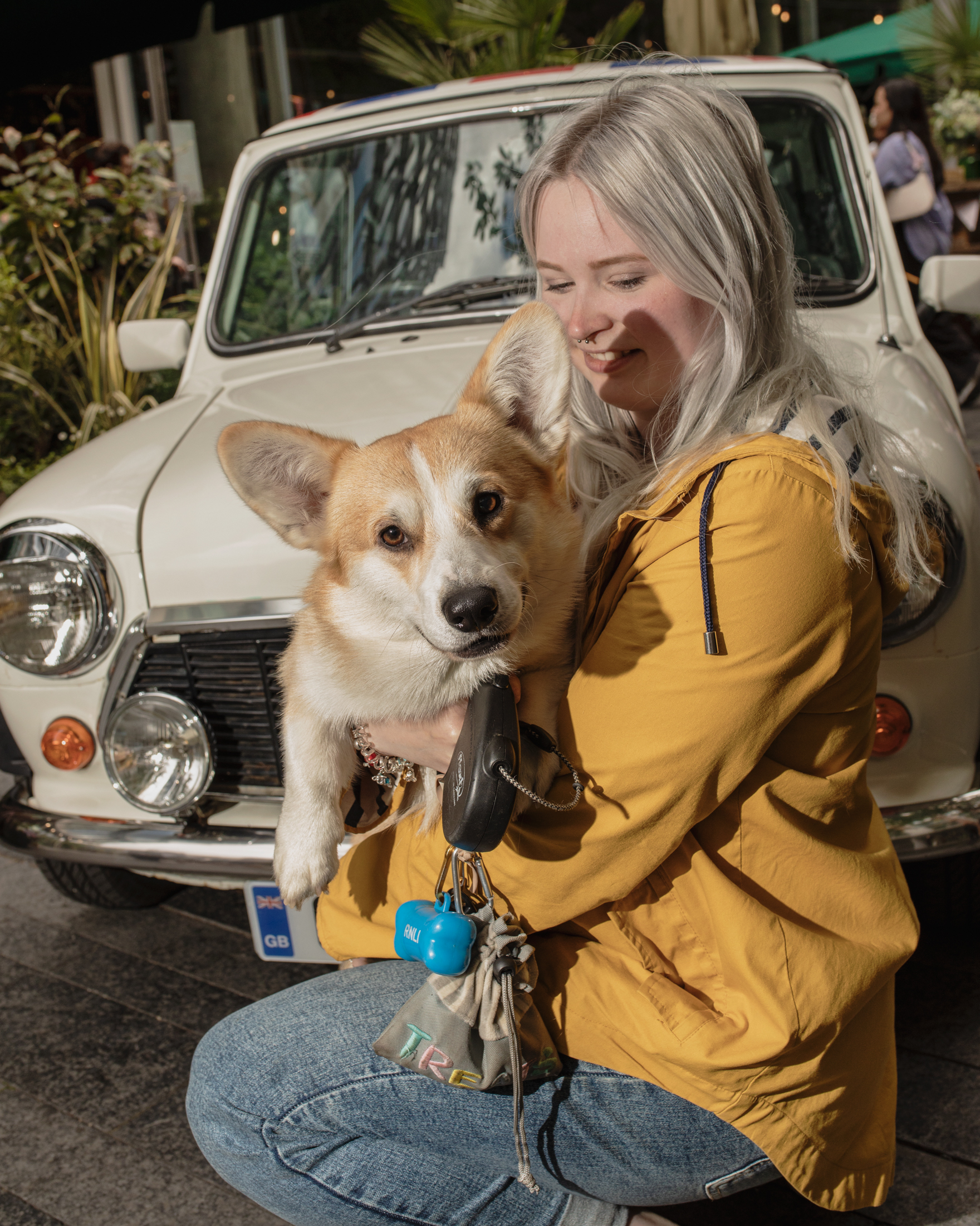 A woman holding her corgi up to her face